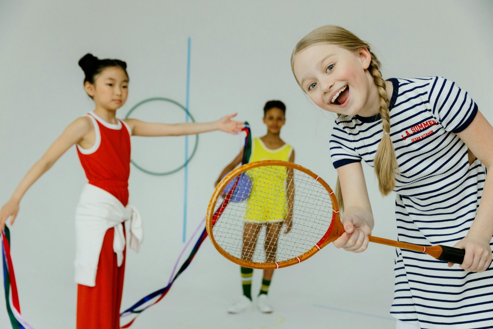 Joyful group of diverse children playing with badminton racket in studio.